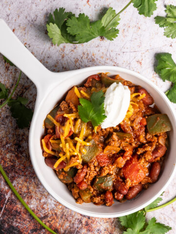 A bowl of chili topped with sour cream and cheese.