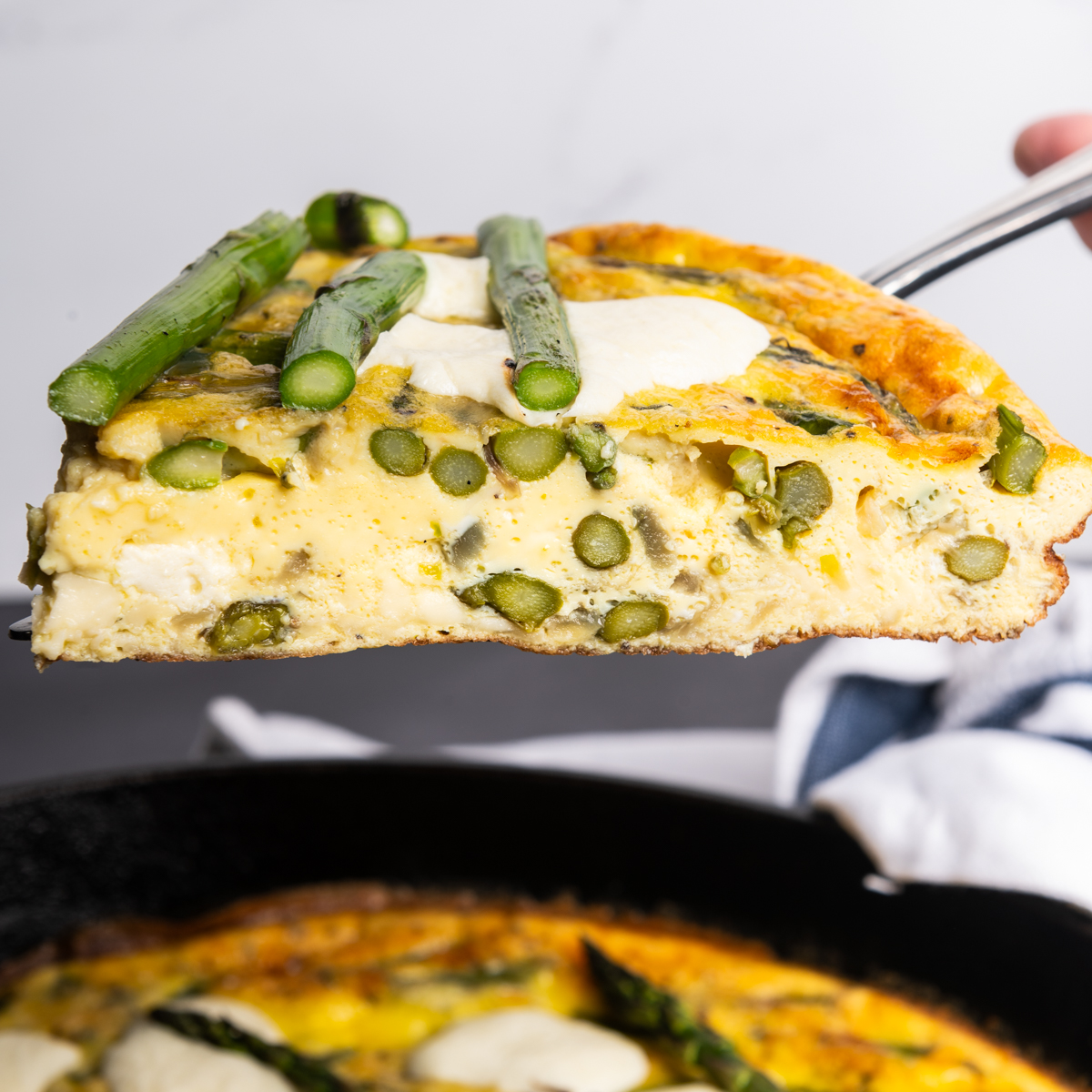 A slice of asparagus frittata showing the creamy inside.